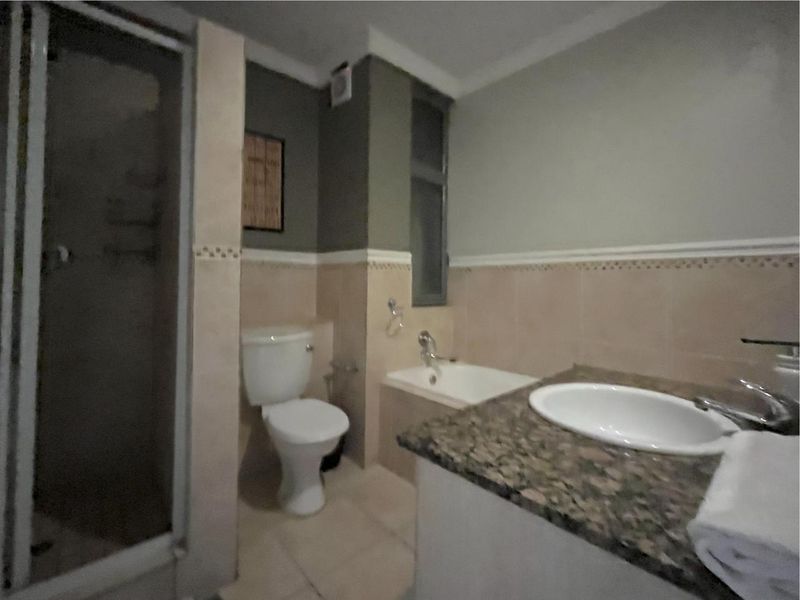 A functional bathroom featuring a shower enclosure, built-in bathtub, toilet, and a vanity with a granite countertop and drop-in sink.