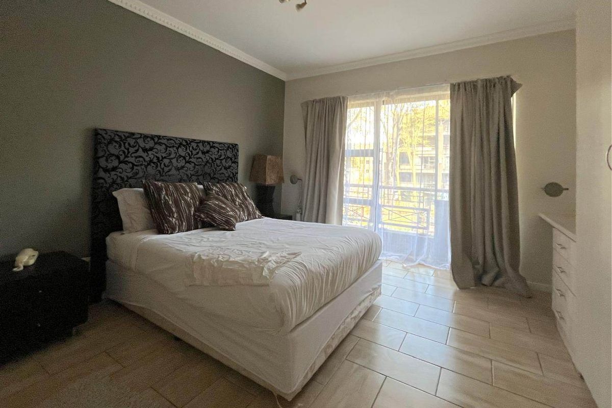 A bedroom featuring tiled flooring, built-in cabinetry, and a sliding glass door providing natural light and access to the exterior.