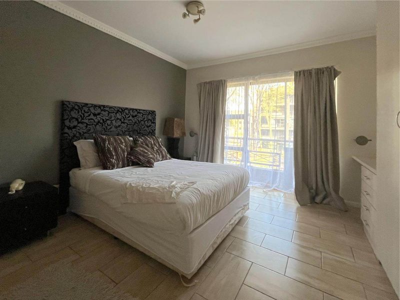A bedroom featuring tiled flooring, built-in cabinetry, and a sliding glass door providing natural light and access to the exterior.