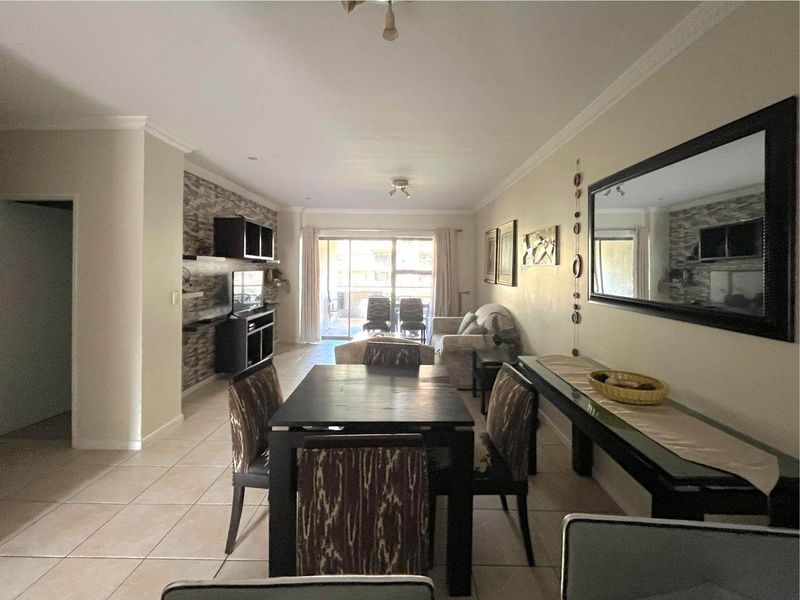 Open plan living and dining area featuring tiled flooring, a stone feature wall, and sliding glass doors leading to an outdoor space.