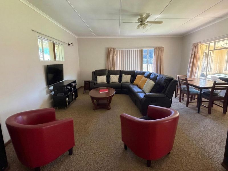 Spacious open-plan living and dining area featuring neutral walls, carpeted flooring, and a ceiling fan, offering a versatile layout for family living.