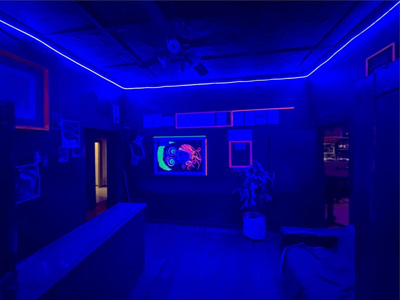 A commercial bar area featuring built-in counter space, ceiling fan, and decorative LED strip lighting throughout the room.