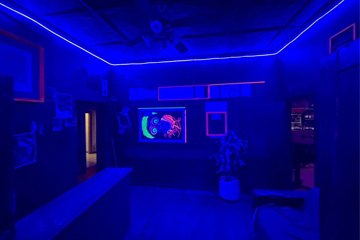 A commercial bar area featuring built-in counter space, ceiling fan, and decorative LED strip lighting throughout the room.