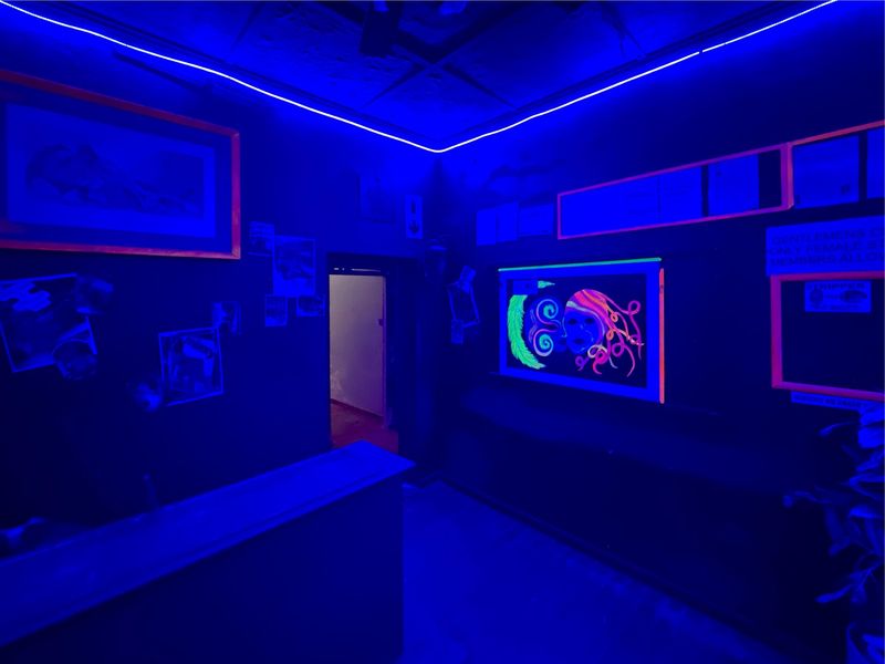 A commercial bar area featuring a built-in counter, recessed ceiling with integrated LED strip lighting, and dark interior finishes.