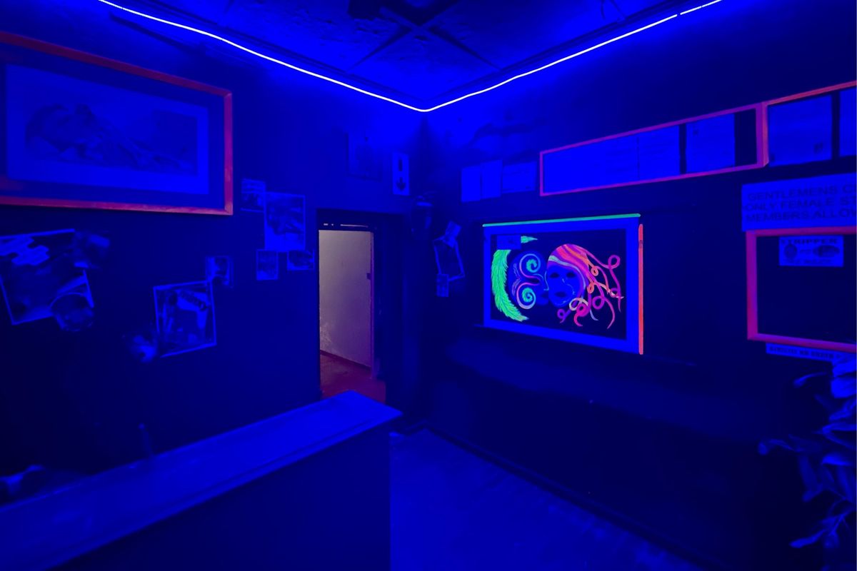 A commercial bar area featuring a built-in counter, recessed ceiling with integrated LED strip lighting, and dark interior finishes.