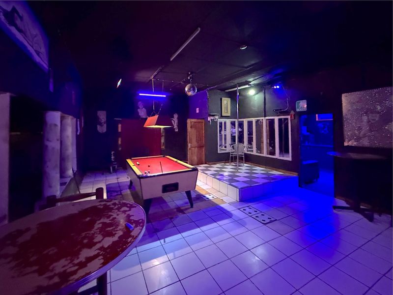Commercial bar area featuring a raised stage, tiled flooring, and integrated lighting fixtures, suitable for entertainment or hospitality use.