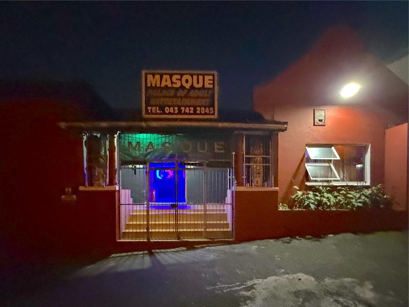 Front exterior view of a commercial property featuring a gated entrance, signage, and exterior lighting at night.