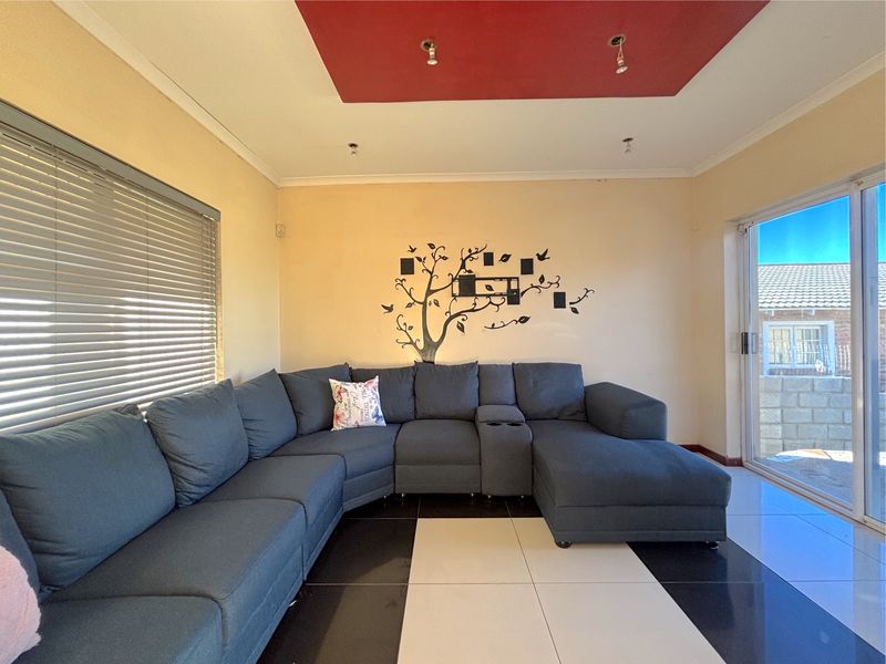 A living room featuring a contrasting black and white tiled floor, a recessed red ceiling detail, and sliding glass doors leading to the exterior.