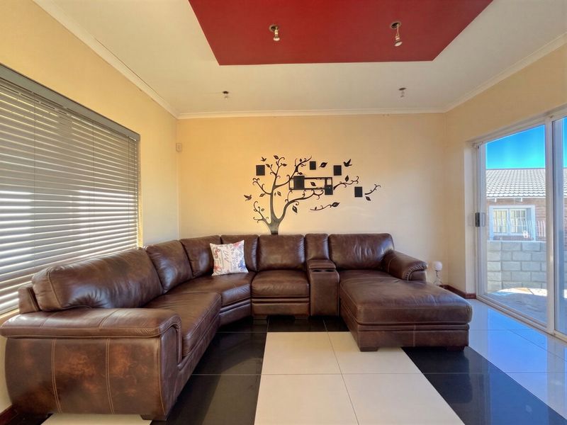 A living room featuring a recessed ceiling detail, large sliding glass doors providing natural light, and contrasting black and white floor tiles.
