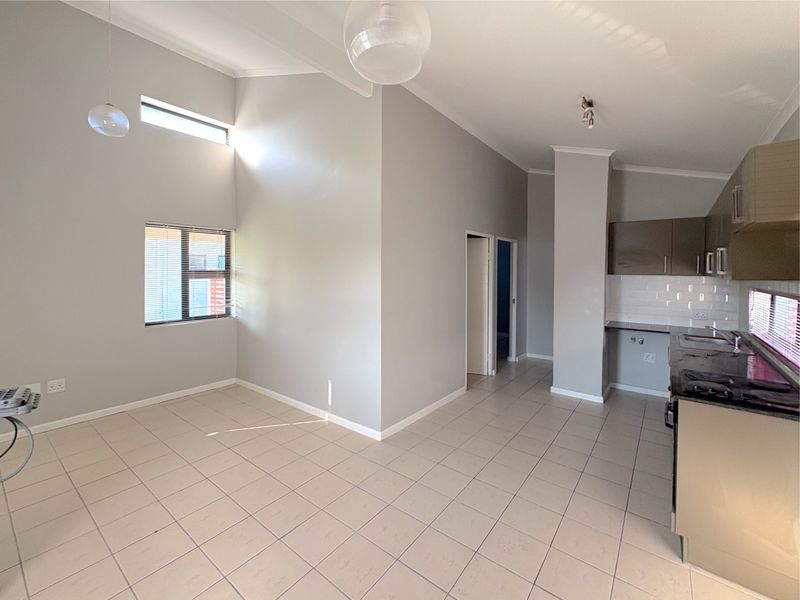 An open-plan living and kitchen area featuring vaulted ceilings, tiled floors, and a modern kitchen with built-in cabinetry and a gas hob.