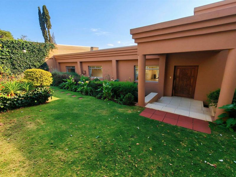 A well-maintained front entrance featuring a tiled porch, decorative wooden door, and a neatly landscaped garden area.