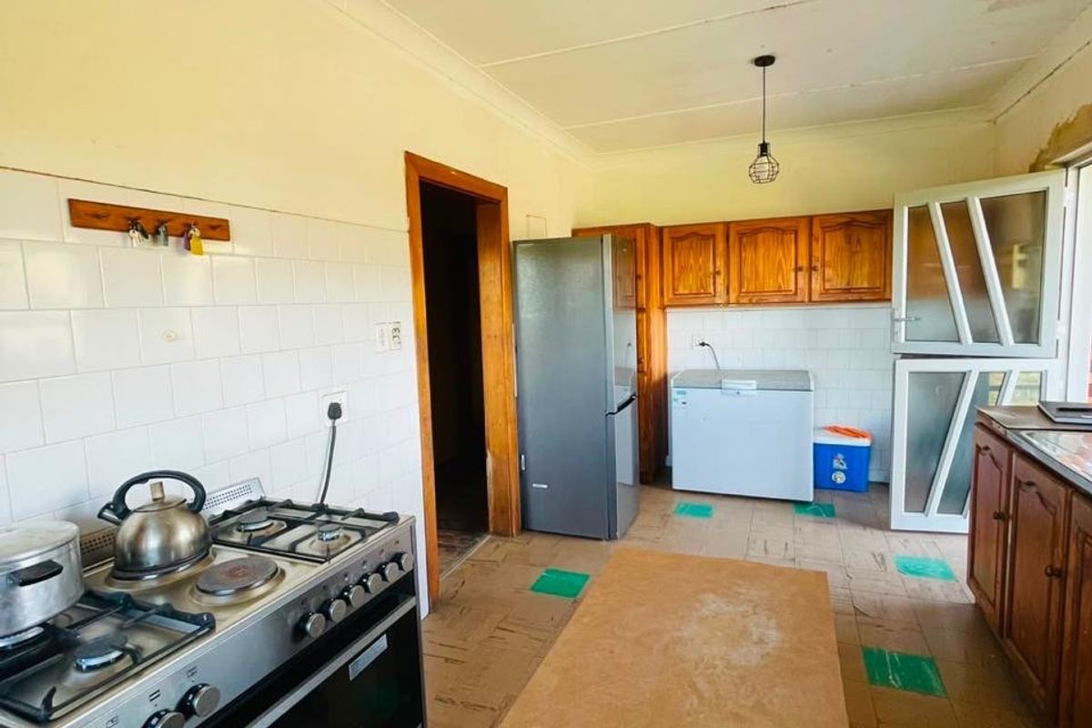 A dated kitchen featuring wooden cabinetry, a gas stove, tiled backsplash, and a stable door, requiring cosmetic updates to improve its overall condition.