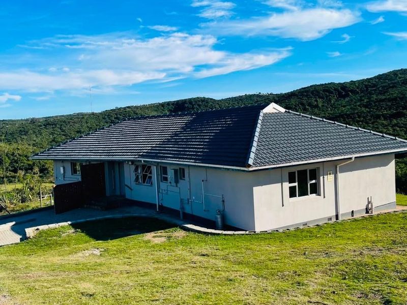 A view of the rear elevation of the farm house featuring a tiled roof and surrounding lawn area.