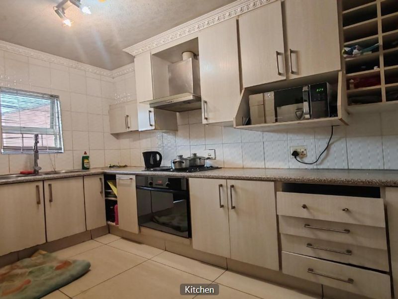 Functional kitchen featuring built-in cabinetry, tiled backsplash, integrated oven and hob, and ample storage space with a dedicated wine rack.