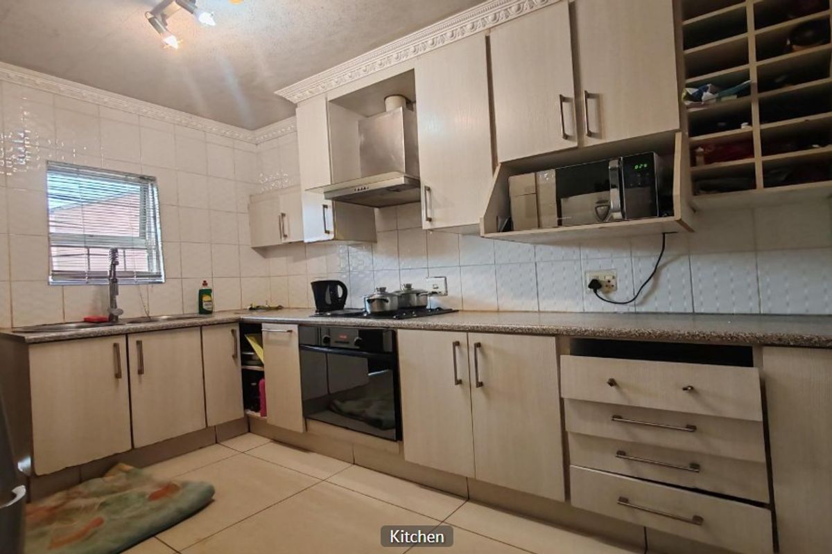 Functional kitchen featuring built-in cabinetry, tiled backsplash, integrated oven and hob, and ample storage space with a dedicated wine rack.