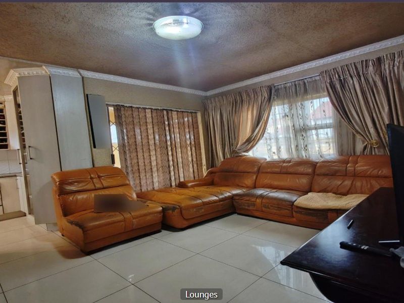 Open plan living area featuring tiled flooring and integrated kitchen cabinetry with ceiling cornice detailing.