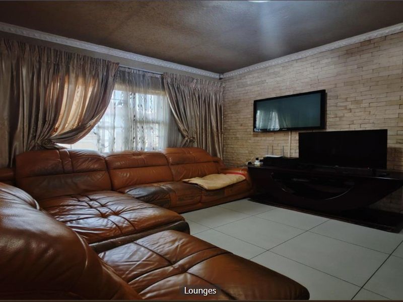 A living room featuring a stone veneer accent wall, tiled flooring, and decorative crown molding.