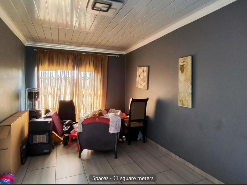 A living room featuring tiled flooring and a tongue and groove ceiling, with access to an exterior area through a security gate.