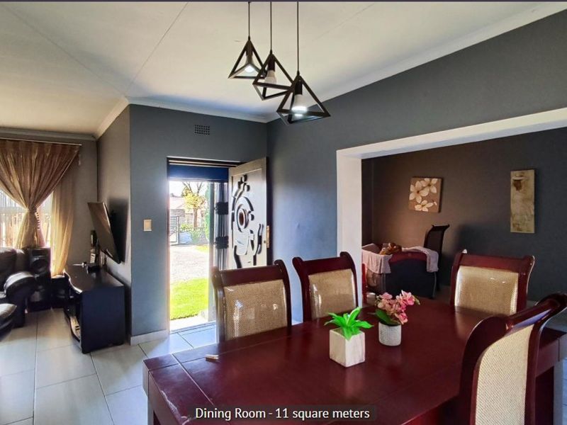 Open plan living and dining area featuring tiled flooring, modern pendant lighting, and direct access to the exterior through a security gate.