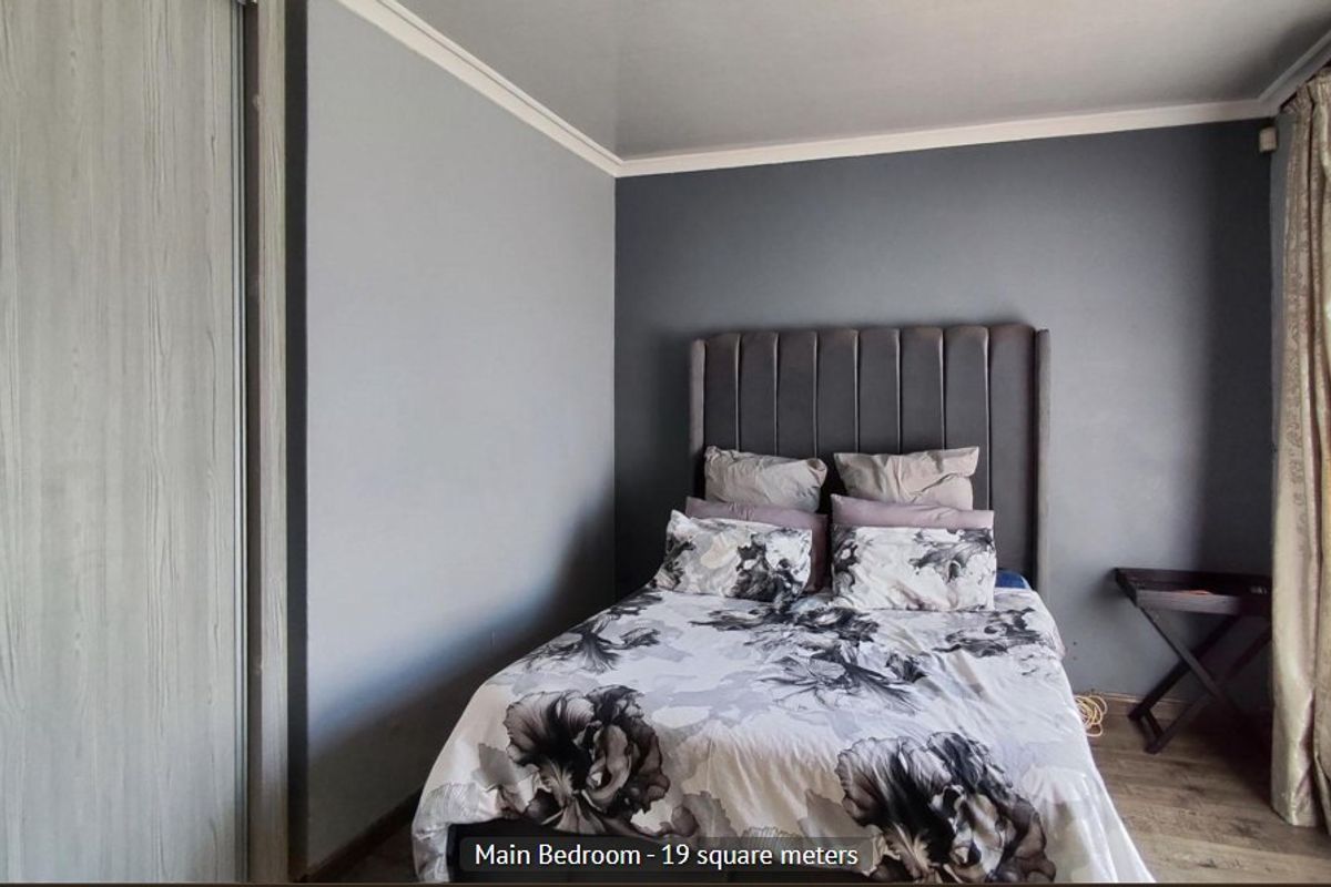 A bedroom featuring laminate flooring, a built-in wardrobe, and neutral wall finishes.