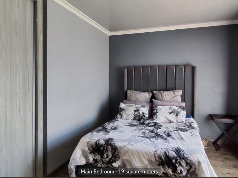 A bedroom featuring laminate flooring, a built-in wardrobe, and neutral wall finishes.
