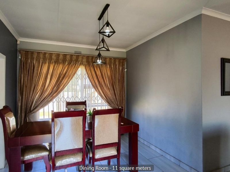 A dining room featuring tiled flooring, decorative pendant lighting, and a window fitted with a security gate.