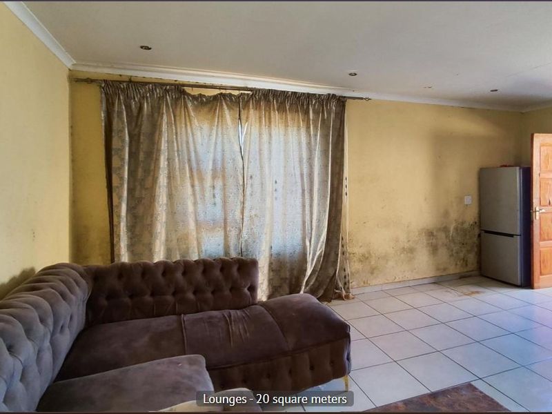 Living room area featuring tiled flooring and recessed lighting, currently showing significant wall staining and signs of wear requiring maintenance.