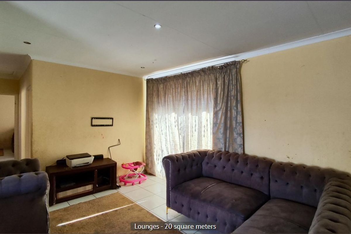 A living room featuring tiled flooring, recessed downlighting, and a sliding glass door. The walls show signs of wear and require repainting.