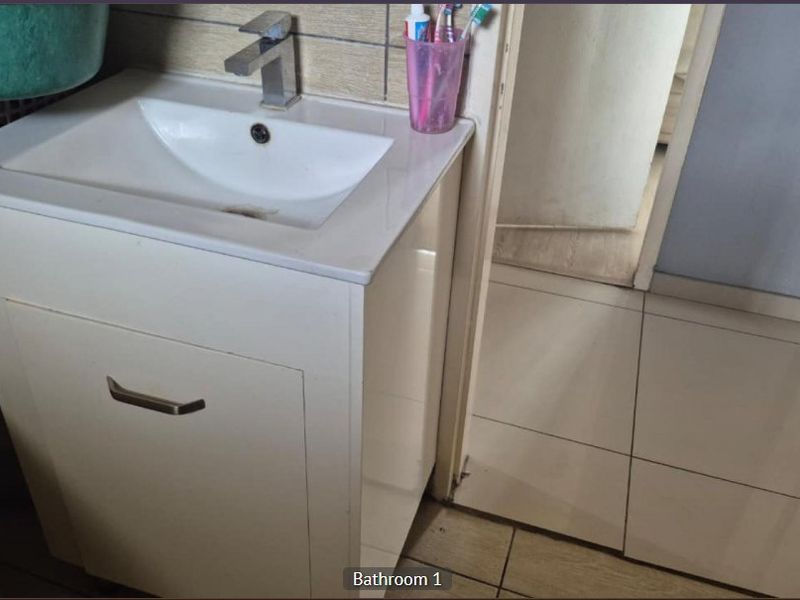 A functional bathroom featuring a white vanity cabinet with a modern mixer tap and tiled flooring.