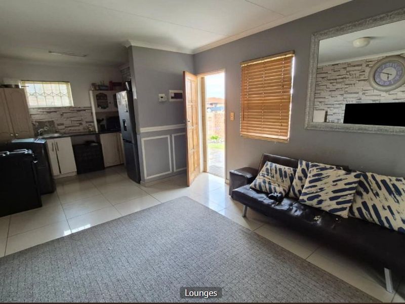 Open-plan living area featuring tiled flooring, integrated kitchen cabinetry, and direct access to the exterior.