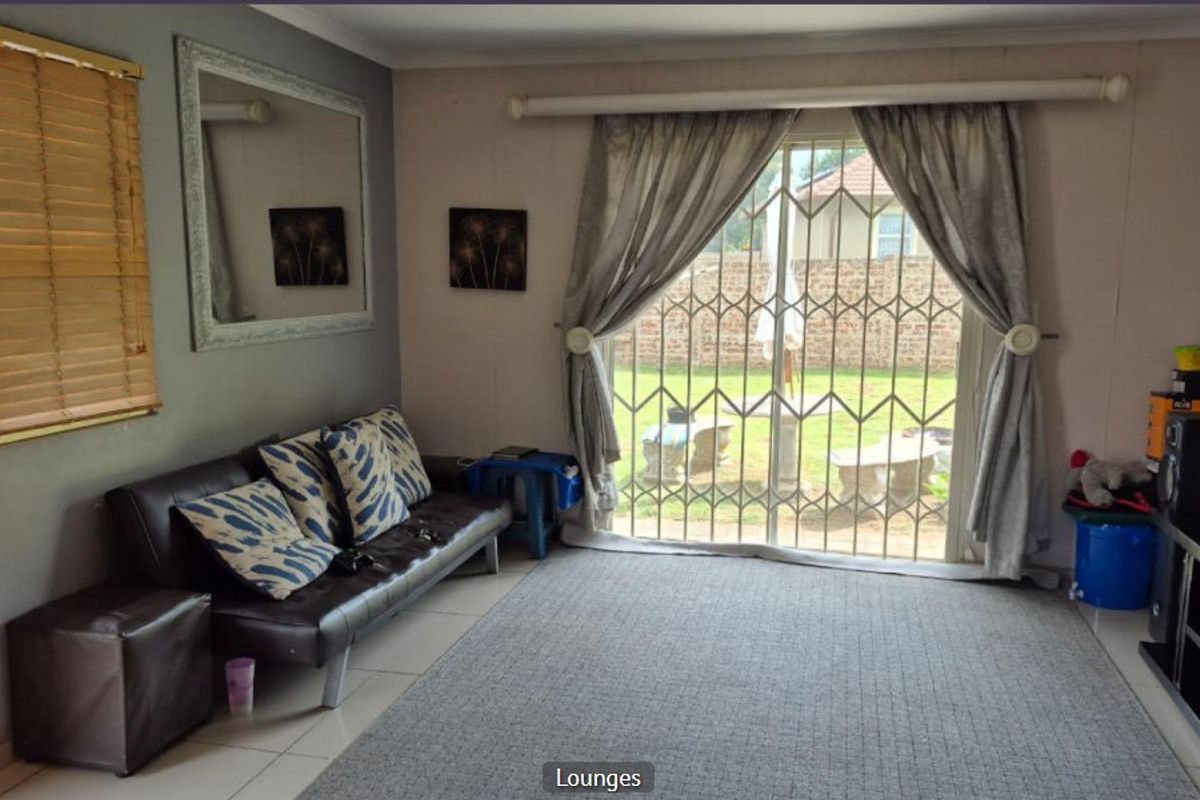 A living room featuring tiled flooring, a sliding glass door with a security gate, and access to the rear garden area.