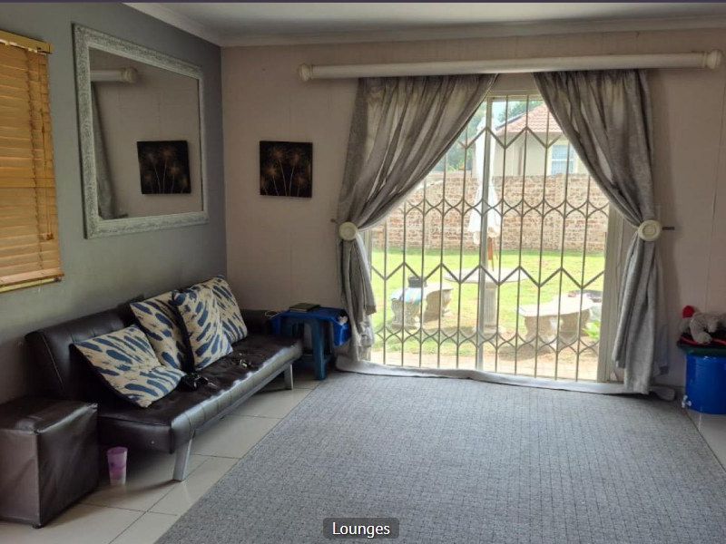 A living room featuring tiled flooring, a sliding glass door with a security gate, and access to the rear garden area.