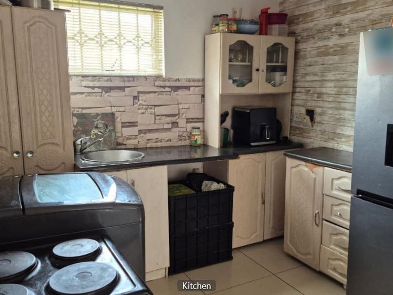 Compact kitchen featuring built-in cabinetry, laminate countertops, a stainless steel sink, and tiled backsplash, offering a functional layout with potential for cosmetic updates.