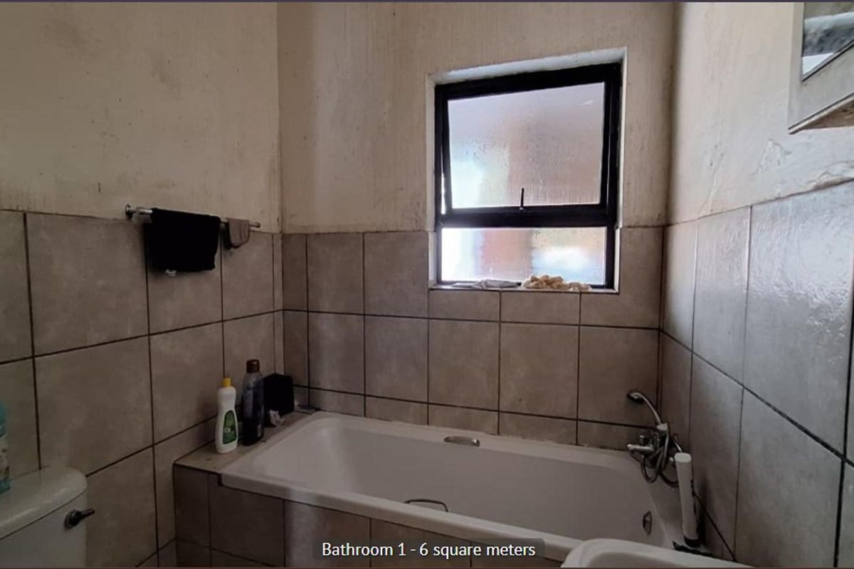 A compact bathroom featuring a bathtub, toilet, and tiled wall finishes, requiring cosmetic updates to improve the overall condition.