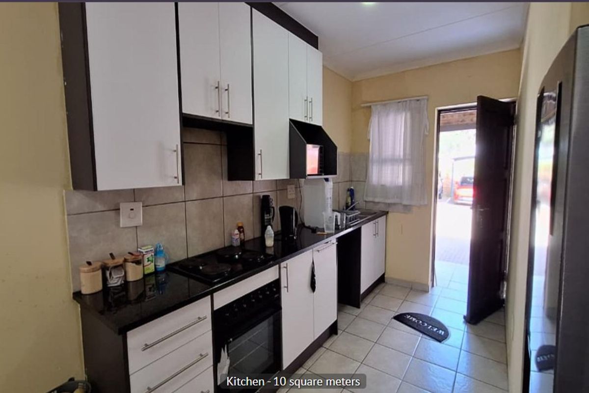 Compact kitchen featuring modern two-tone cabinetry, granite countertops, built-in oven and hob, tiled backsplash, and direct access to the exterior.