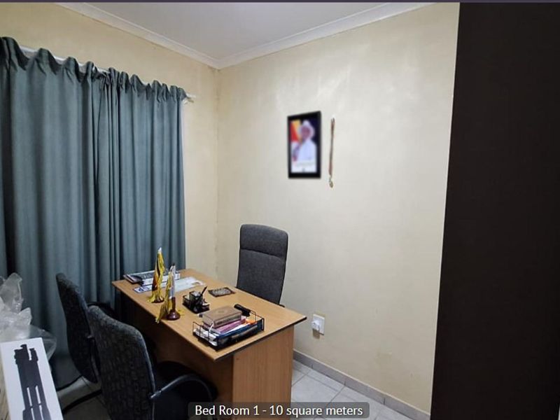 A compact bedroom featuring tiled flooring and neutral wall finishes, currently utilized as a home office space.
