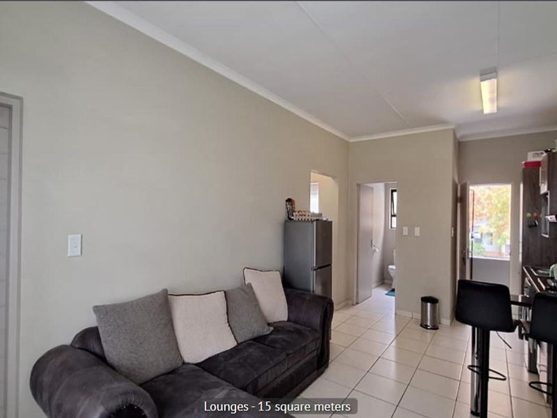 Open-plan living area featuring tiled flooring and a compact kitchen with built-in cabinetry, providing a functional layout for modern apartment living.