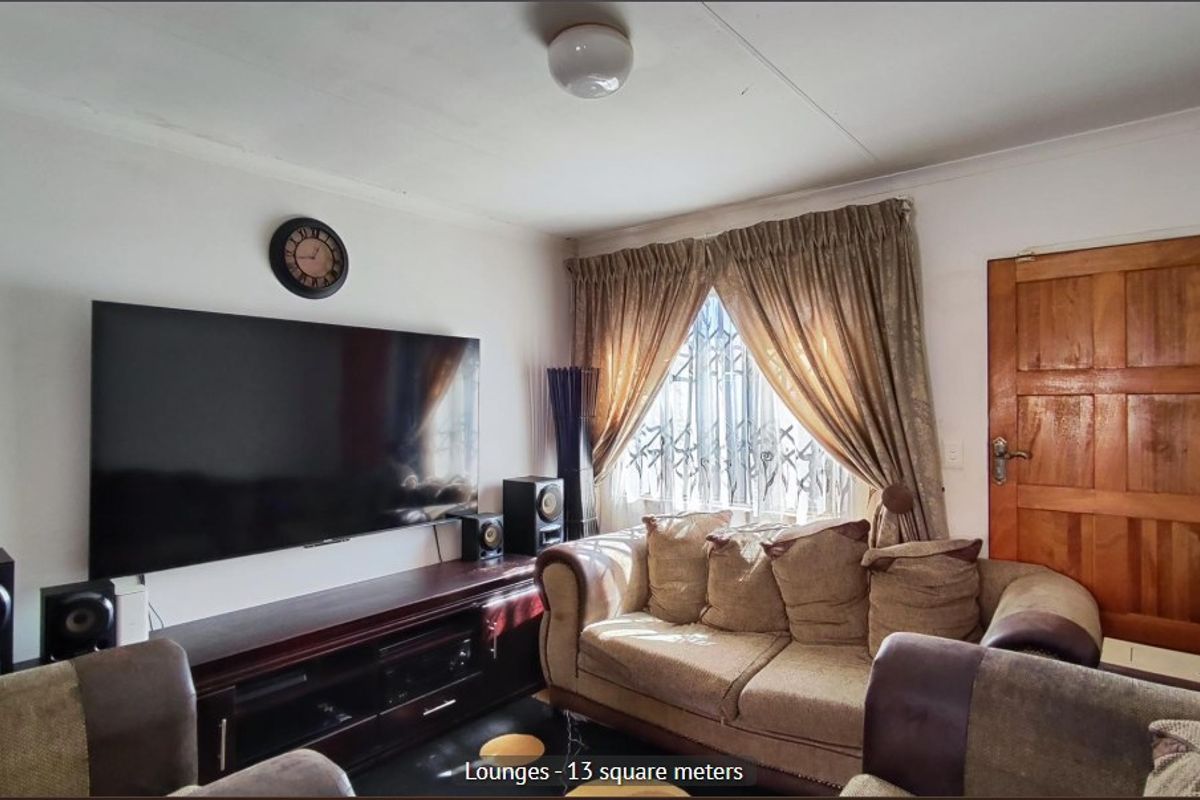 A compact living room featuring a wooden door, security gate on the window, and standard ceiling lighting.