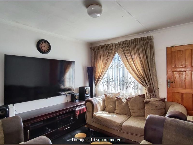 A compact living room featuring a wooden door, security gate on the window, and standard ceiling lighting.