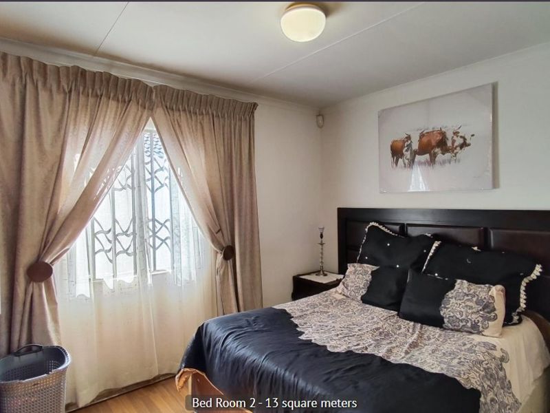 A bedroom featuring laminate flooring, a built-in wardrobe, and a window fitted with a security gate.