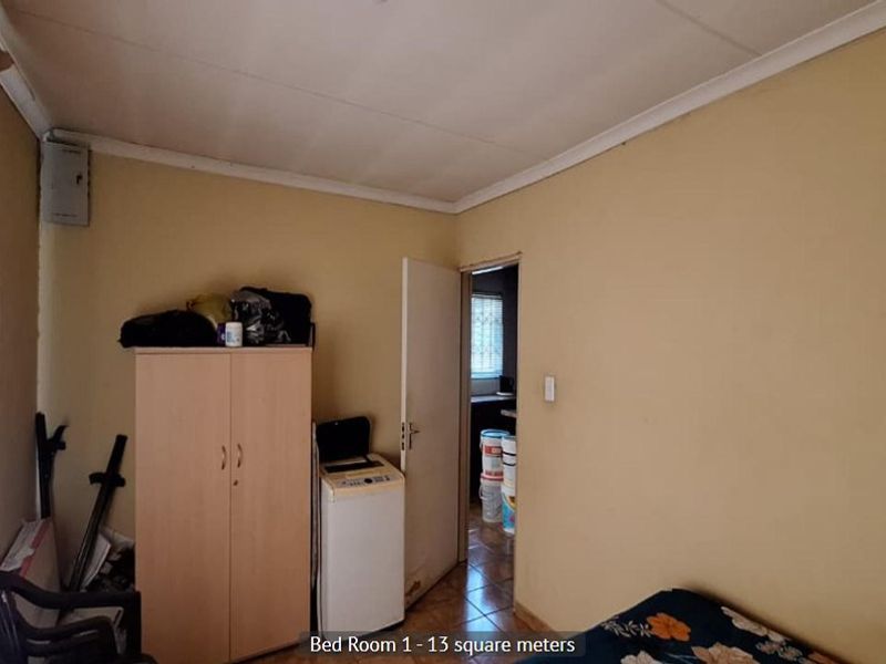 A bedroom featuring a standard layout with a visible electrical distribution board and access to an adjacent room.