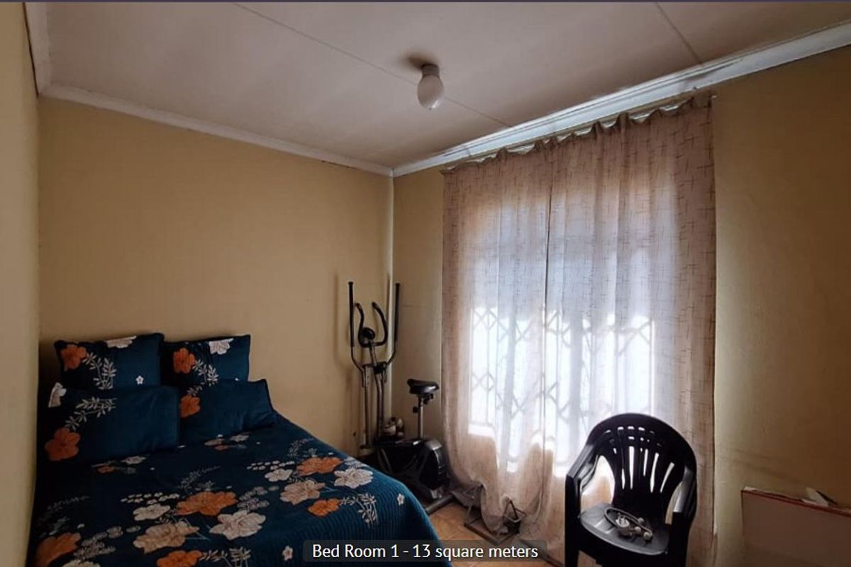 A bedroom featuring a security gate on the window and basic finishes, requiring cosmetic updates to improve its overall condition.