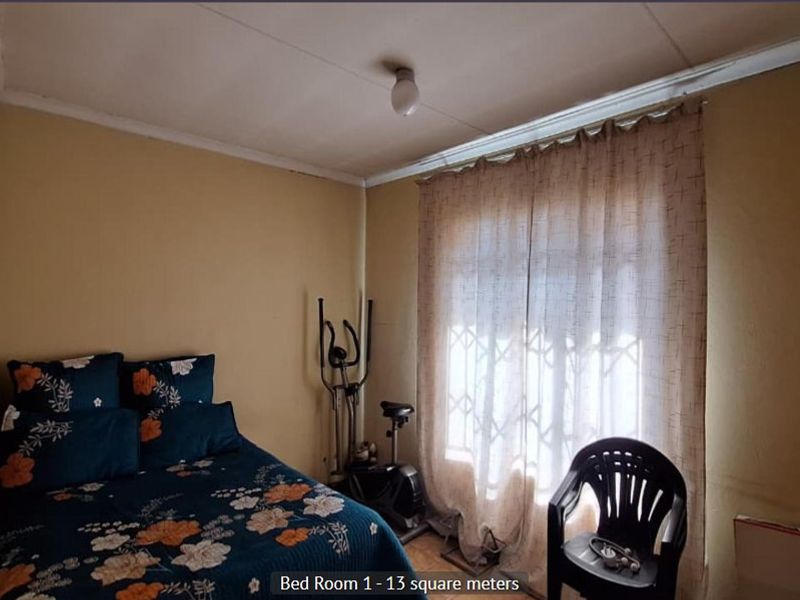 A bedroom featuring a security gate on the window and basic finishes, requiring cosmetic updates to improve its overall condition.
