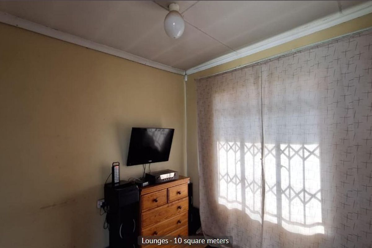 A compact living area featuring a security gate on the window, standard ceiling finishes, and neutral wall paint.