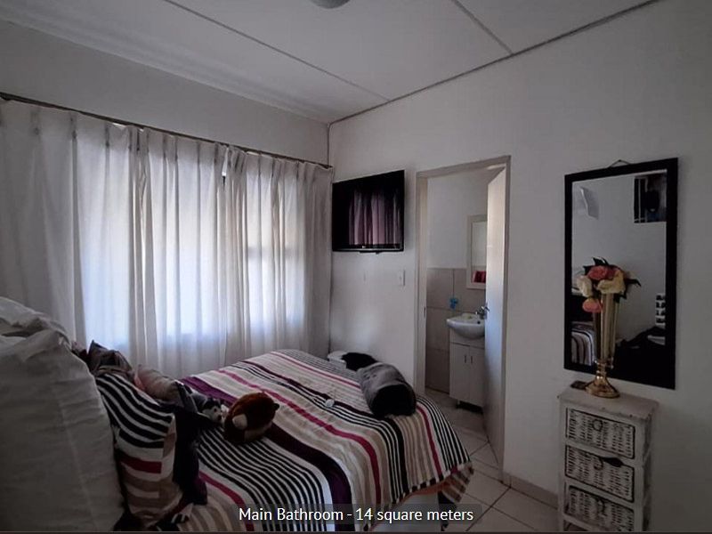 A bedroom featuring tiled flooring and an en-suite bathroom access point, providing a functional living space.