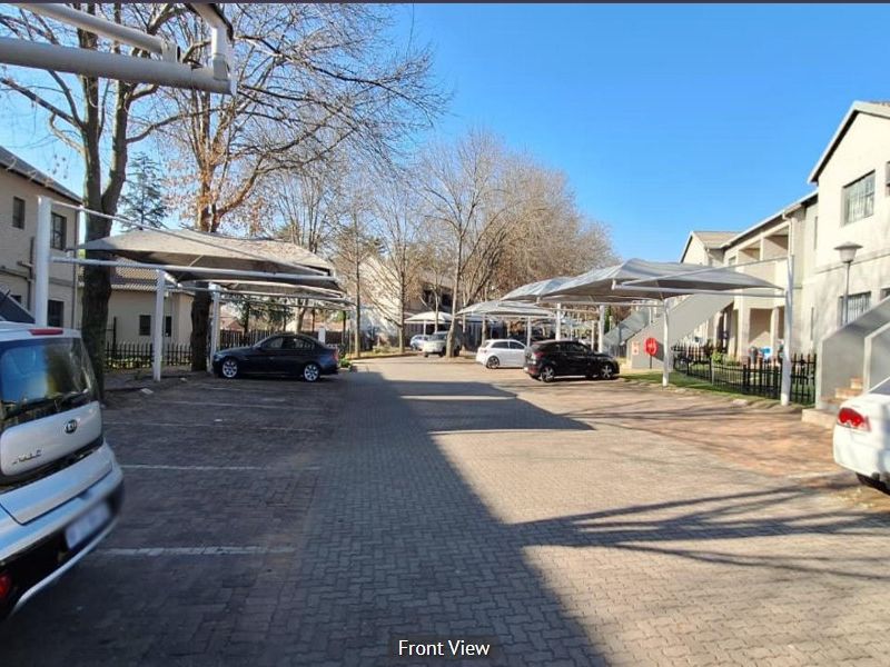 Exterior view of the apartment complex parking area featuring paved driveways and covered shade cloth parking bays.