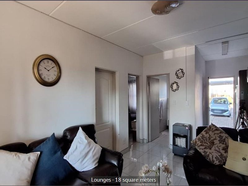 A living room area featuring tiled flooring and access to adjacent rooms, providing a functional space for relaxation.