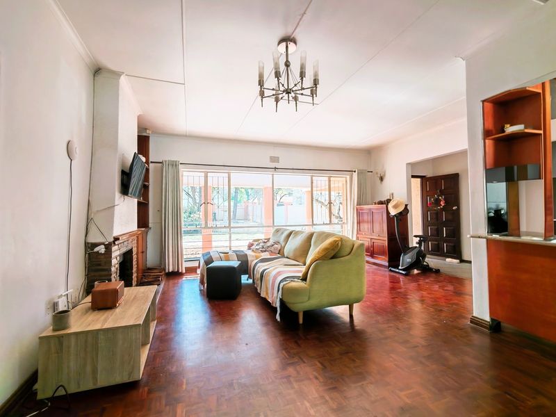 Spacious living room featuring classic parquet flooring, a brick fireplace, and large sliding doors that provide ample natural light and access to the exterior.