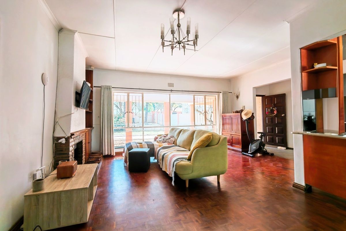 Spacious living room featuring classic parquet flooring, a brick fireplace, and large sliding doors that provide ample natural light and access to the exterior.