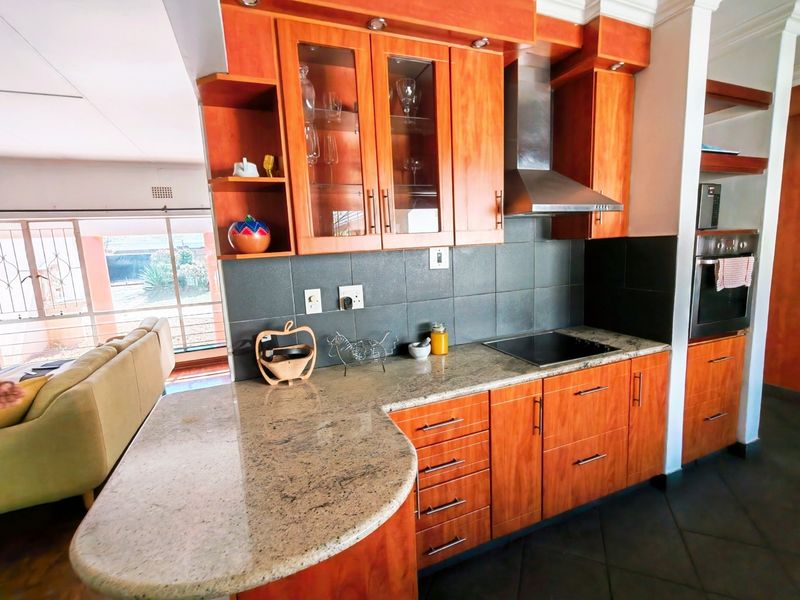 A well-maintained kitchen featuring warm-toned wooden cabinetry, granite countertops, a built-in oven, and a modern stainless steel extractor fan.